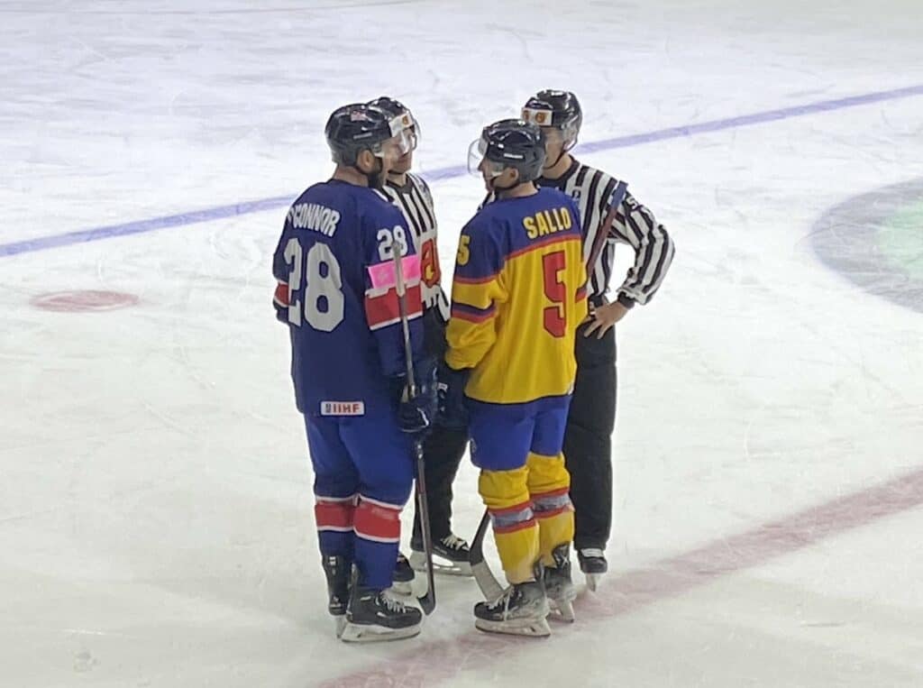 Two Hockey Players From Opposing Teams Discuss A Penalty With Two Referees