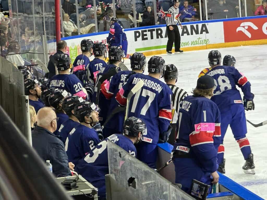 Ice Hockey Players In Blue Jerseys Watch An Ice Hockey Game From The Bench