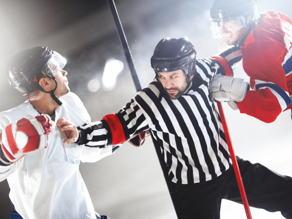 An Ice Hockey Referee Holds Out His Arms To Separate Two Arguing Players During An Ice Hockey Game HIt In Hockey